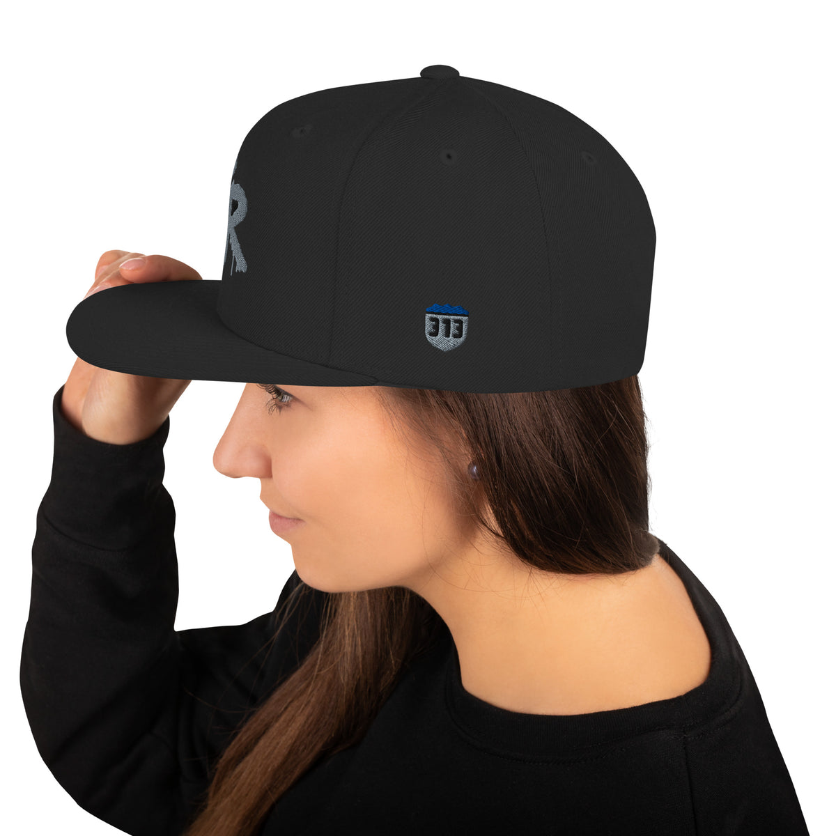 Left side of the black Concrete Fairways snapback on a model, with the embroidered 313 shield